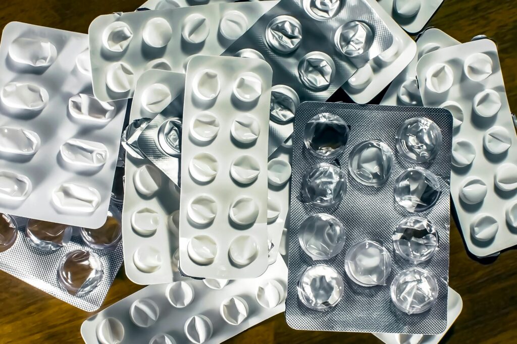 Close-up of various empty blister packs for medications on a wooden surface.